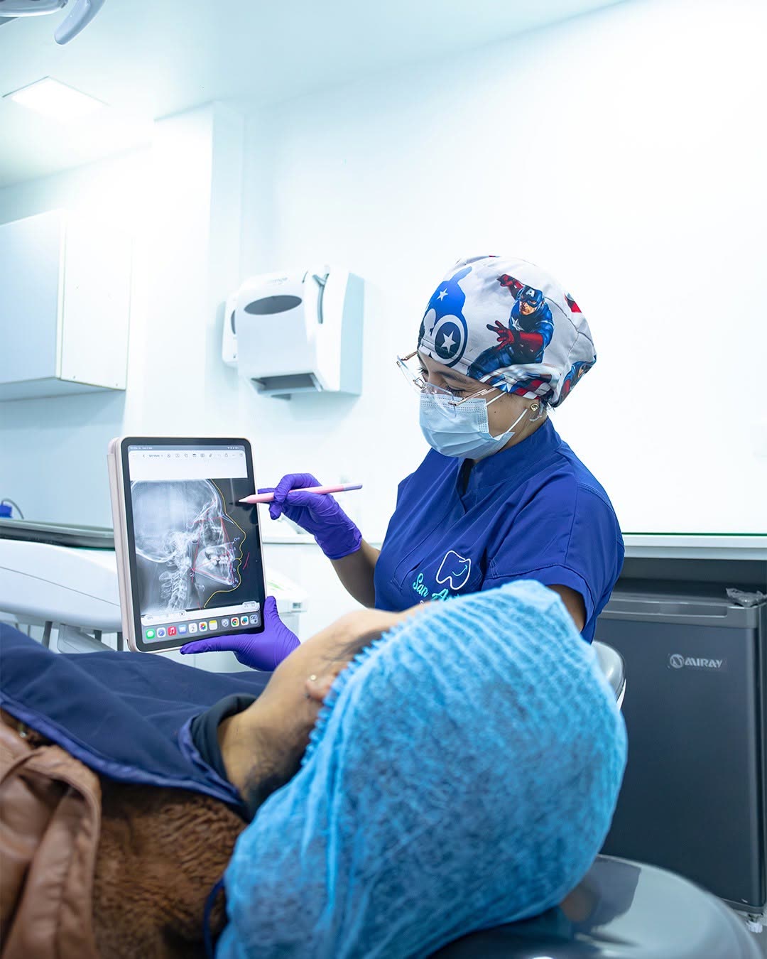 Odontóloga de San Antonio Salud Dental mostrando una radiografía cefalométrica en una tableta a un paciente